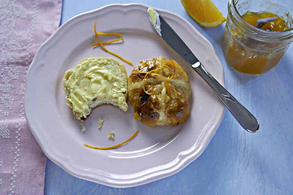 Hot cross bun with butter and orange marmalade — Stock Photo, Image