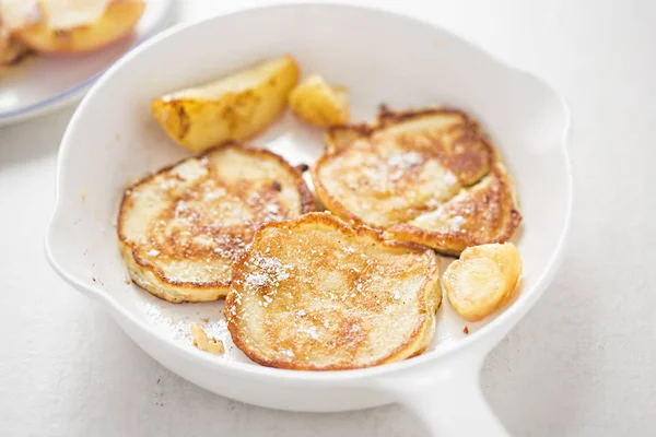 Apple pancakes on white pan