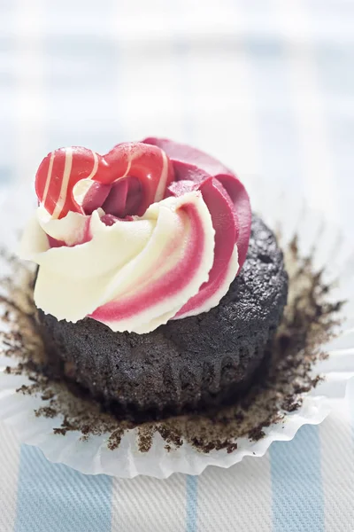 Chocolate sponge cupcake topped with raspberry vanilla frosting and white chocolate decoration — Stock Photo, Image
