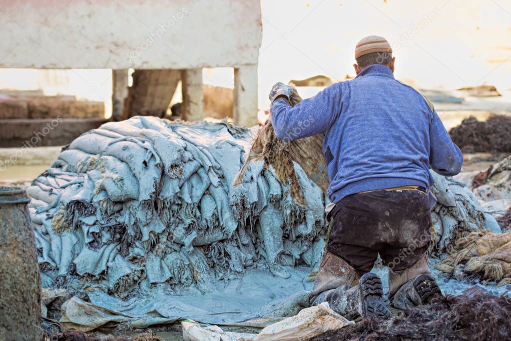 Craftsman applying paint on leather in tanning factory Marrakech medina 