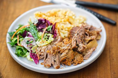 Çekti domuz patates püresi ve beyaz tabakta karışık yaprakları salata ile 