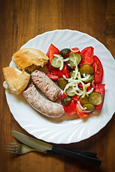 White sausage with gherkin, tomato, onion salad and fresh roll