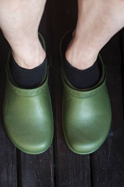 Siyah çoraplı adam tarafından giyilen yeşil crocs takunya 