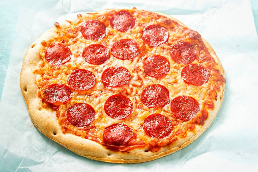 Pizza with cheese and pepperoni on blue surface 