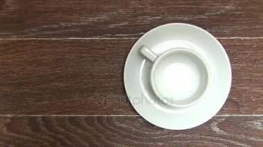 Kahverengi masa üzerinde uçan daire ile boş beyaz kahve fincanı
