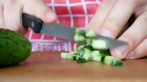 Las manos cortando sabroso pepino verde en la tabla de cortar con cuchillo — Vídeos de Stock