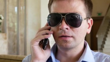 Siyah gözlük kör adam otelde telefonla konuşuyor