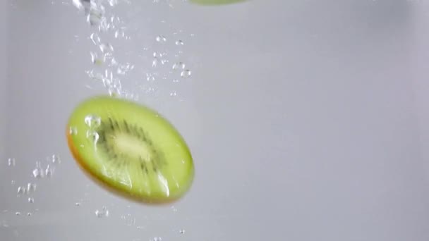 Segmenten van kiwi fruit vallen in water — Stockvideo