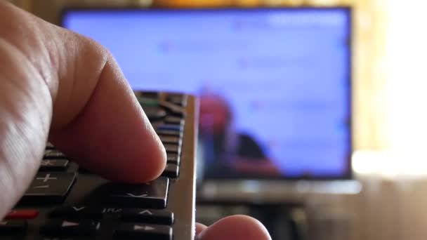 Рука тримає телевізійний пульт дистанційного керування і зміни телевізійних каналів — стокове відео