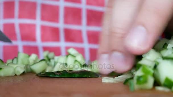 Handen snijden groene komkommer op hakken bord met mes — Stockvideo