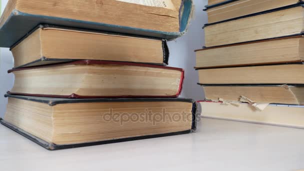 Estudante olha para pilha de livros na mesa — Vídeo de Stock
