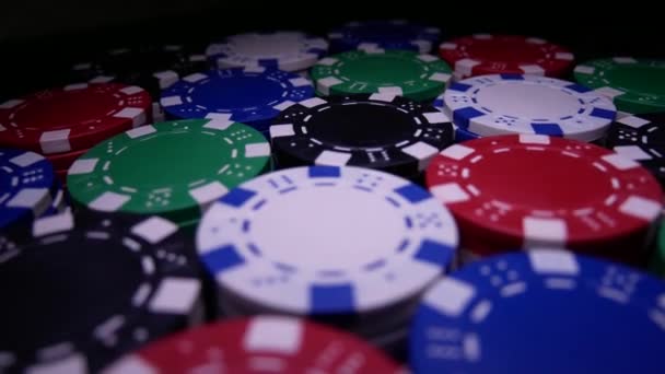 Viele Pokerchips drehen sich in der Dunkelheit auf dem Tisch — Stockvideo