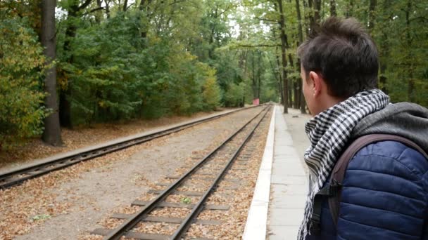 Ein junger Mann wartet auf einen Zug — Stockvideo