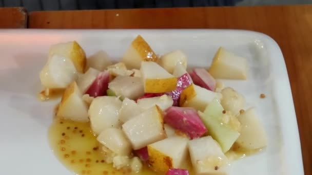Рука делает салат с розовым китайским красным мясом редиска и желтой грушей — стоковое видео