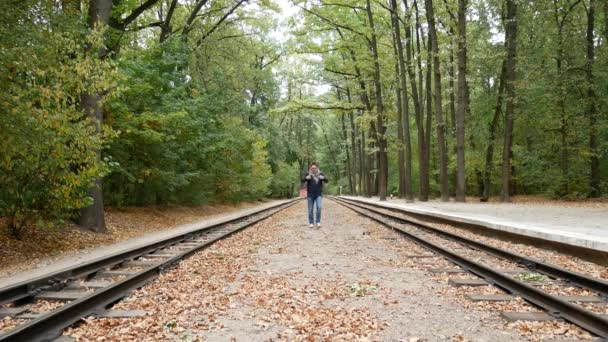 El hombre camina por la plataforma entre los rieles del ferrocarril — Vídeo de stock