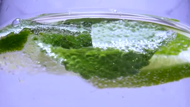 Slices of lime and mint leaves in liquid with clear Drink — Stock Video