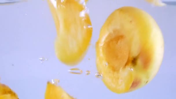 Органические абрикосы, падающие в воду — стоковое видео