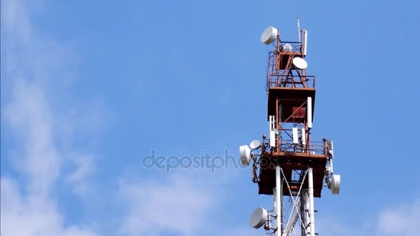Телекоммуникационная башня с антеннами и ретрансляторами против голубого неба и облаков — стоковое видео