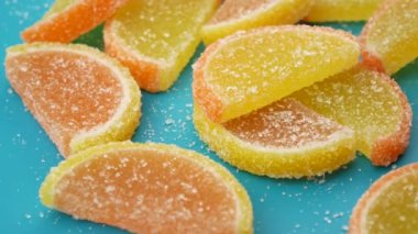 Kırmızı ve sarı tatlılar yeşil bir arka plan üzerinde dönen şekerlenmiş meyve jelly şeker