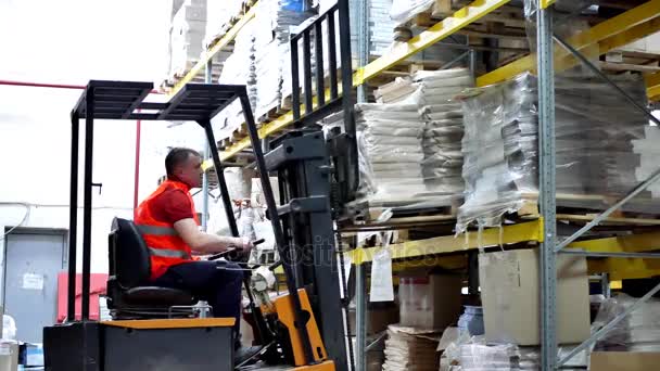 Рабочий водитель, перевозящий вилочный погрузчик на складе — стоковое видео