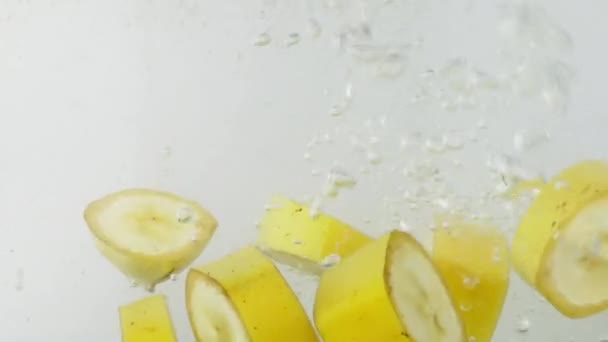 Кусок банана падает в воду — стоковое видео