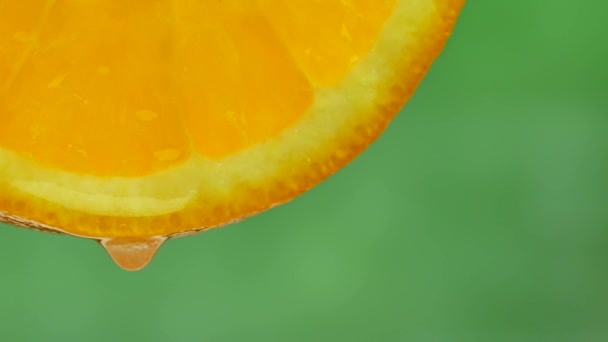 Droppe rent vatten eller juice droppande från en bit av orange — Stockvideo