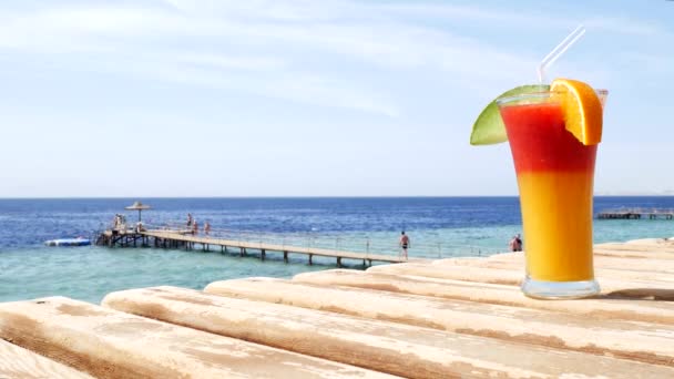 Röd jordgubb och mango juice på blå och turkosa havet bakgrund eller ocean — Stockvideo