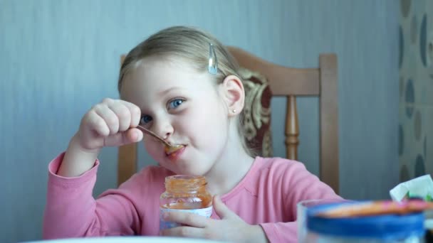 小蓝眼睛女孩与金发吃勺子在厨房的水果泥或酱在家里 — 图库视频影像