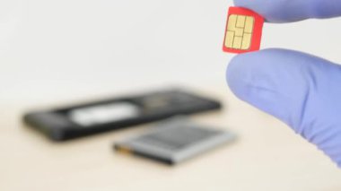 Demonte cep telefonu arka plan üzerinde kırmızı mikro-SIM kartı tutan el