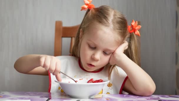 Bambina mangia un cucchiaio con una ciotola bianca — Video Stock