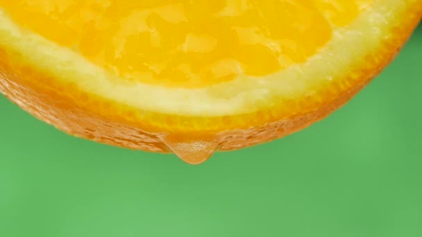 Droppe rent vatten eller juice droppande från en bit av orange — Stockvideo