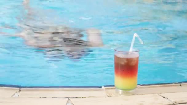 Schöne Frau schwimmt in einem Pool und trinkt einen bunten Cocktail — Stockvideo