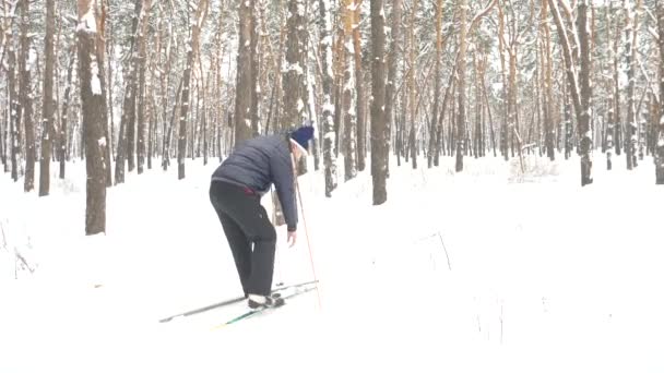 Старший мужчина надевает лыжи зимой — стоковое видео