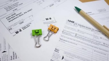 Taxes Form 1040, W-2 and W-9 with Smiles Binder Clips and Pen