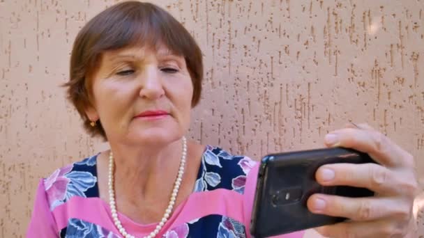 Siyah akıllı telefon kullanan kıdemli yetişkin yaşlı kadın. — Stok video