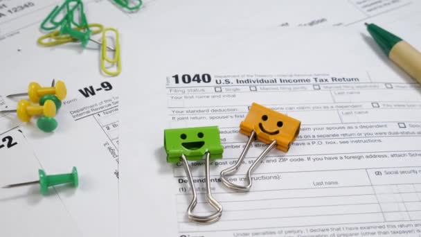 Formularz podatkowy W-9 i 1040 z klipsami usmiechającymi na stole — Wideo stockowe