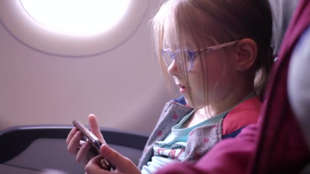 Маленькая девочка с помощью смартфона на самолете — стоковое видео