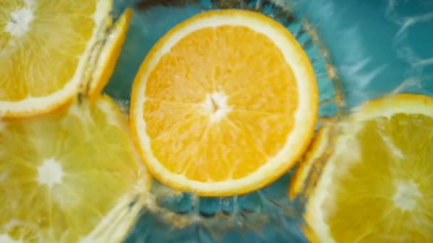 Frische Orangen fallen in Wassersaft mit riesigen Spritzern — Stockvideo