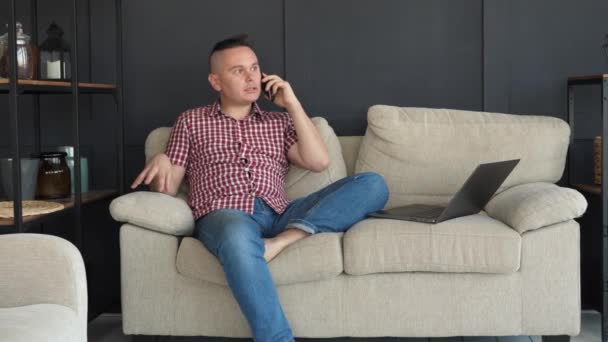 Человек на диване разговаривает по смартфону — стоковое видео