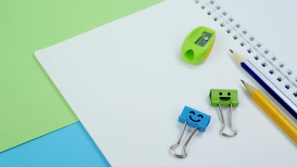 Groene en blauwe glimlach binder clips met gele potloden op notitieblok — Stockvideo