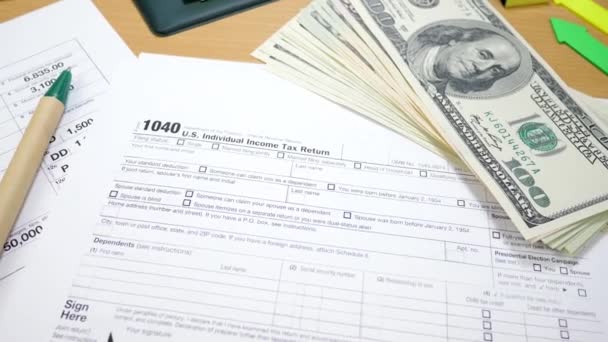 Pacote de contas de 100 dólares e 1040 Formulário de imposto na tabela — Vídeo de Stock