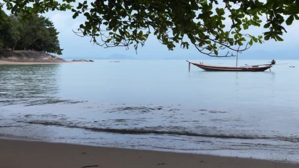 Perspectiva bonita da praia arenosa sobre o mar calmo com barco de pesca pequeno — Vídeo de Stock