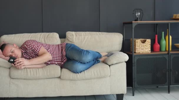 Freiberufler mit Smartphone liegt auf Sofa — Stockvideo