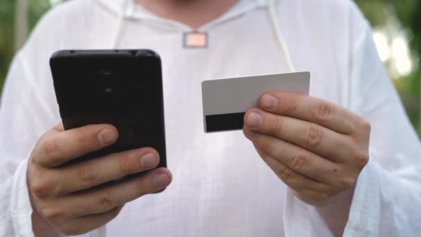 Mężczyzna korzystający z czarnego smartfona i karty płatniczej — Wideo stockowe