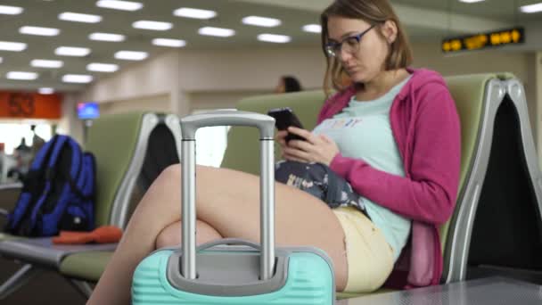 Young tourist female person use smartphone at departure in airport — Stock Video