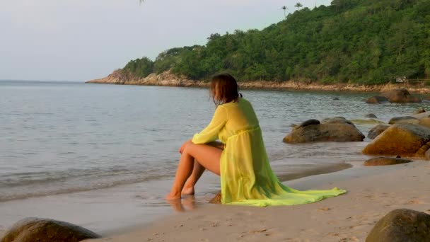 Hermosa mujer se sienta en piedra en la playa de mar — Vídeo de stock