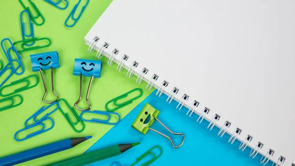 Green and Blue Office Paper Clip, Smile Binder Clips and Pencils on Notepad