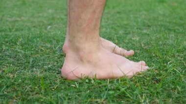 Man Enjoys Walking On Green Grass Barefoot