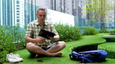 Freelancer male uses black laptop on green grass