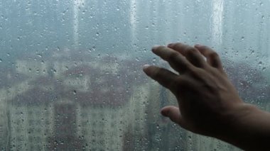 Males hand touch glass window at rain day